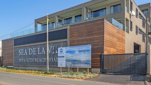 A modern building with a large sign advertising 'SEA DE LA VIE' at 182 South Beach Road, featuring oceanfront living and a starting price of R995,000. - Sea De La Vie 25 (La Mercy)