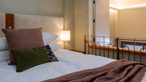 A neatly made bed with a white headboard, multiple pillows, and a blanket. - Gaynor Clayton Apartment (Dunedin)