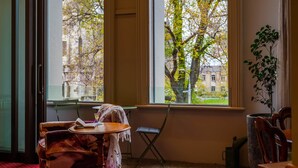 A room with a table and chairs near a window with a view of trees and buildings. - Gaynor Clayton Apartment (Dunedin)