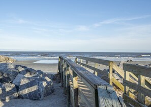 Walk along the beach path lined with large rocks to the ocean's edge.
