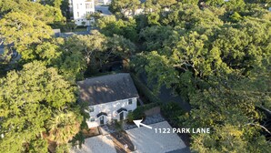 Vista aérea de un barrio residencial con una casa en 1122 Park Lane, rodeada de abundante vegetación, y un acceso a la playa visible al fondo.