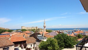 A coastal town with traditional architecture, a prominent tower, and a historic fort. - Otel Meryem Ana Bozcaada (Bozcaada)