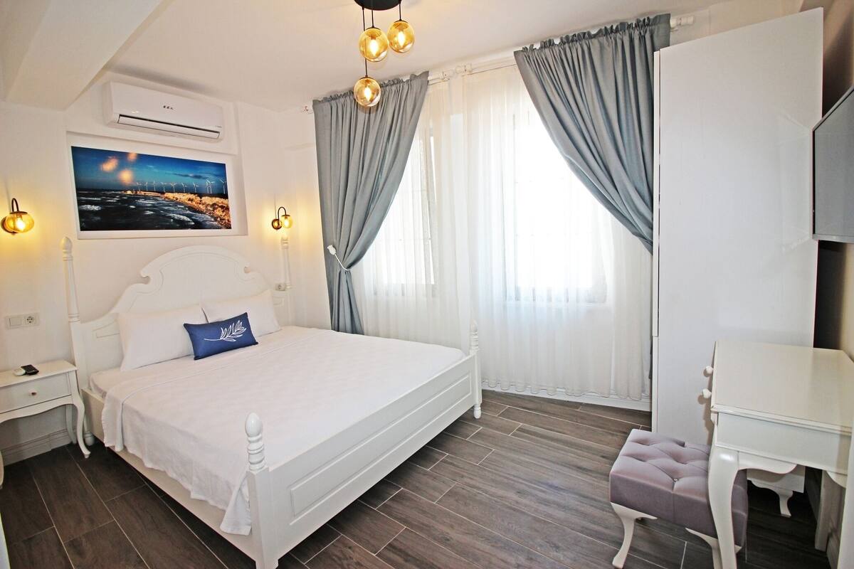 A bedroom with a bed, bedside tables, a desk, and a chair.