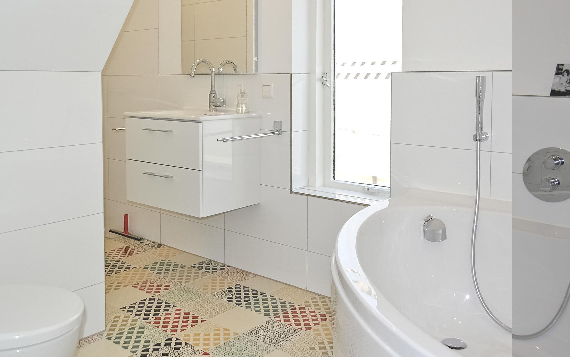 Une salle de bain moderne avec une baignoire sur pieds, un meuble-lavabo avec un miroir et un carrelage décoratif.