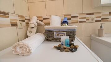 A bathroom with a white towel, a wicker basket labeled "Home," and toiletries on the counter.