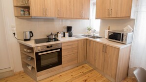 Une cuisine compacte avec des meubles en bois, un four encastré, un four à micro-ondes et une machine à café.