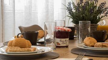 A breakfast setting with croissants, a glass of jam, and a coffee cup on a wooden table.