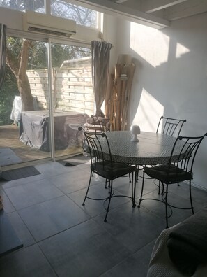 Un comedor con una mesa y sillas, una puerta corrediza de vidrio que da a un patio exterior y una pared de ladrillo.
