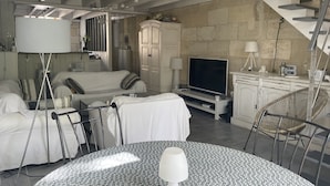 Een moderne woonkamer met een zithoek, een televisie, een eettafel en een trap.