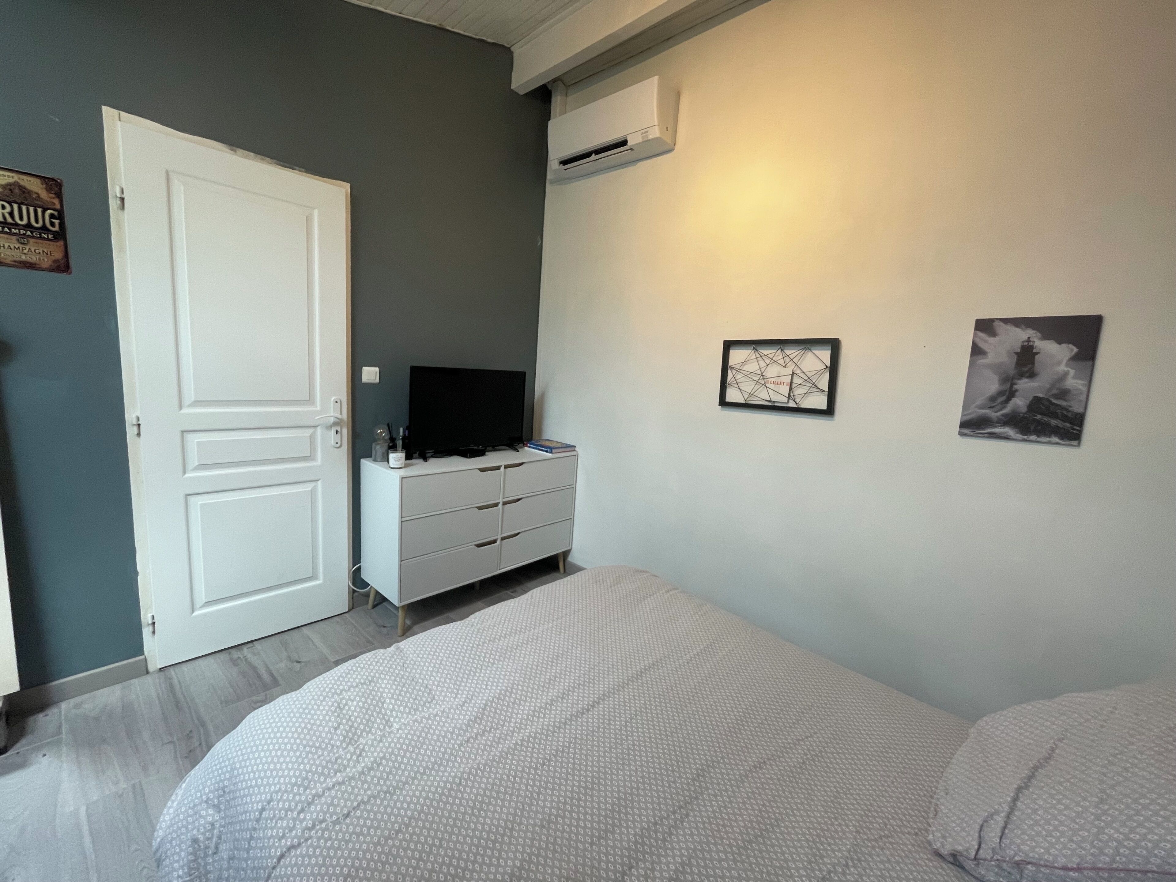 A bedroom with a bed, a dresser, a television, and two framed pictures on the wall.