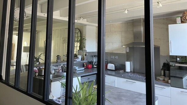 Een moderne keuken met een groot raam, roestvrijstalen apparatuur en uitzicht op de tuin.