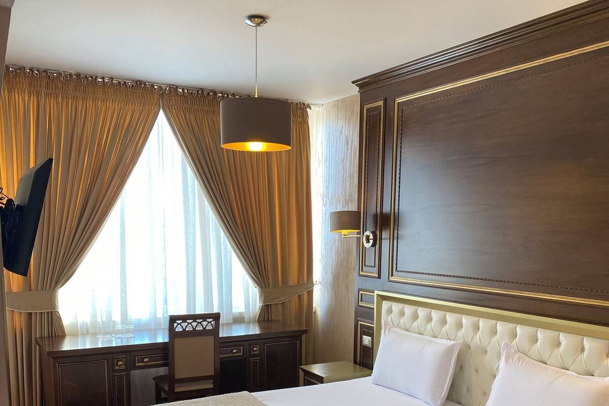 Ein Hotelzimmer mit einem großen Bett, einem Schreibtisch, einem Stuhl und einem an der Wand befestigten Fernseher.