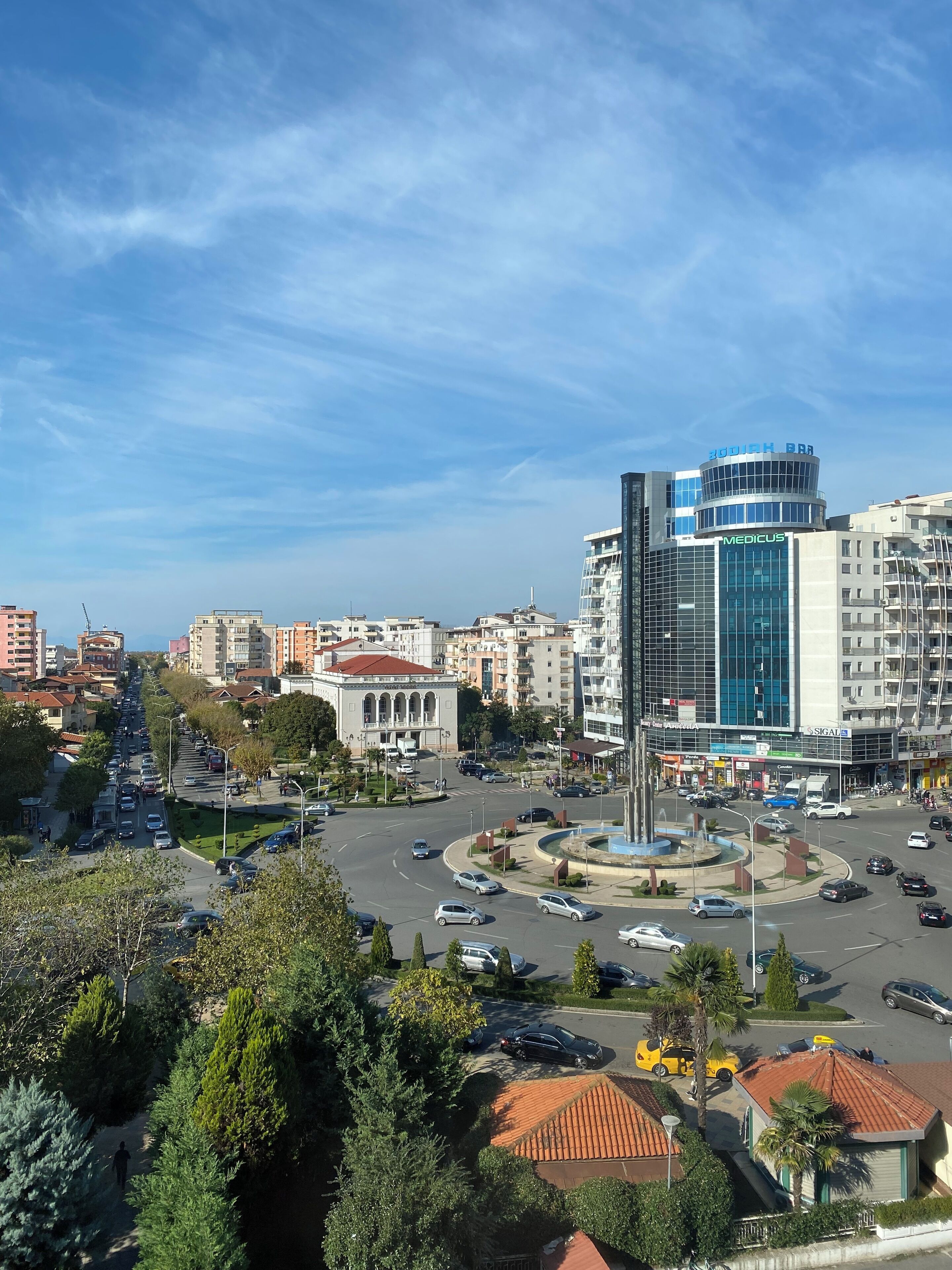 A cityscape with a prominent building labeled 'Medicus' and a roundabout with vehicles.