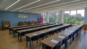 Ein Konferenzraum mit langen Tischen und Stühlen, Flaggen und einem großen Fenster mit Blick auf die Stadt.