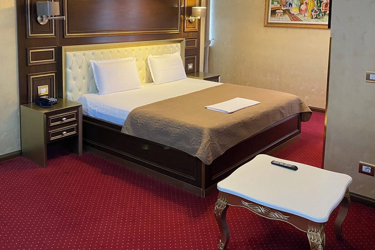 Ein Hotelzimmer mit einem großen Bett, einem Nachttisch, einem Schreibtisch und einem Bild an der Wand.
