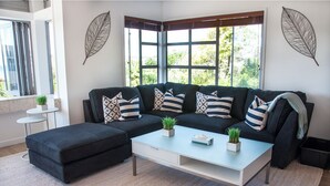 Una sala moderna con un sofá modular, una mesa de centro y un adorno de hojas en la pared.