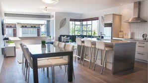 Una cocina moderna con una isla central, taburetes de bar y un comedor con mesa y sillas.