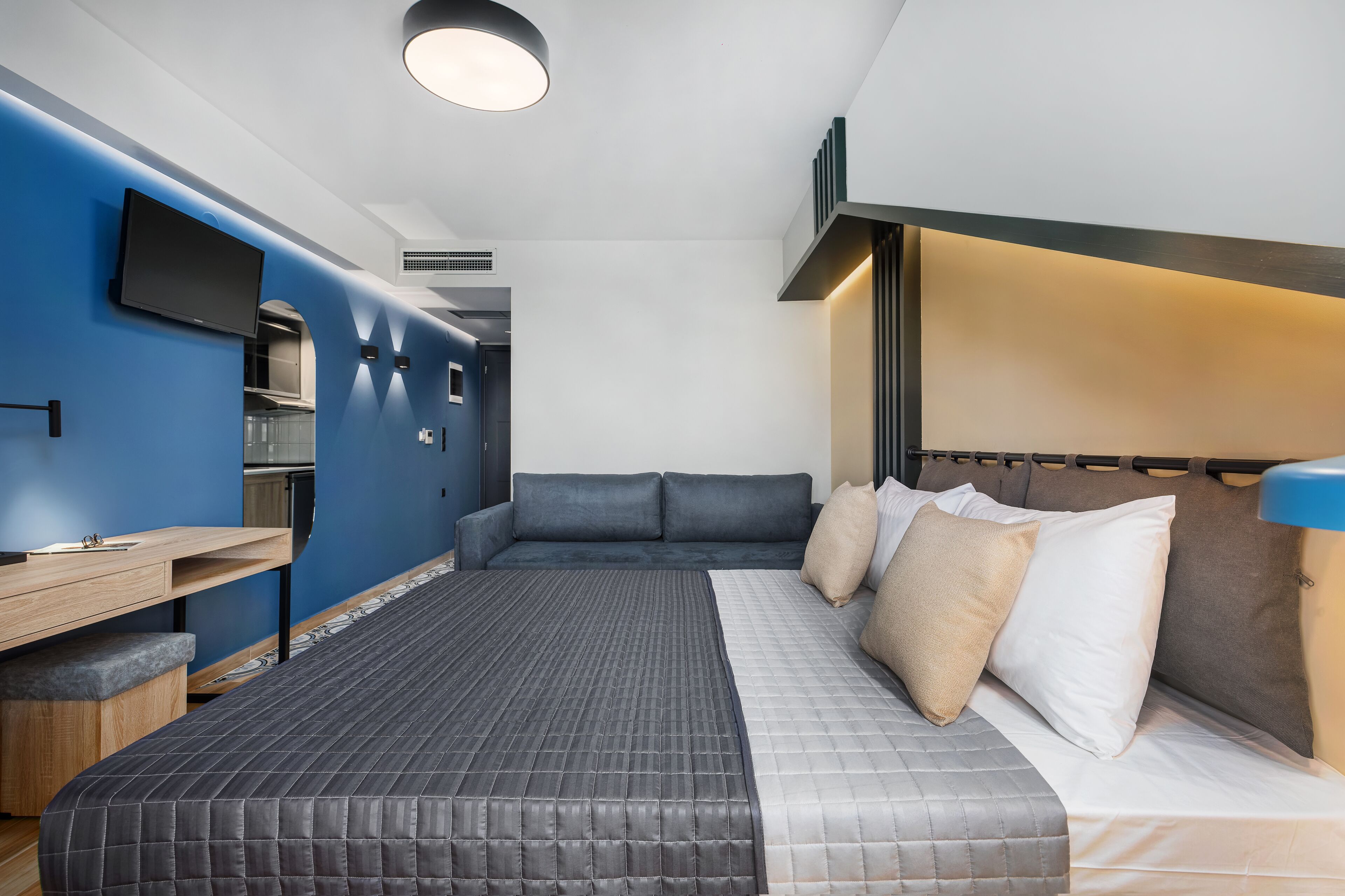 A modern hotel room with a bed, a desk, and a TV.
