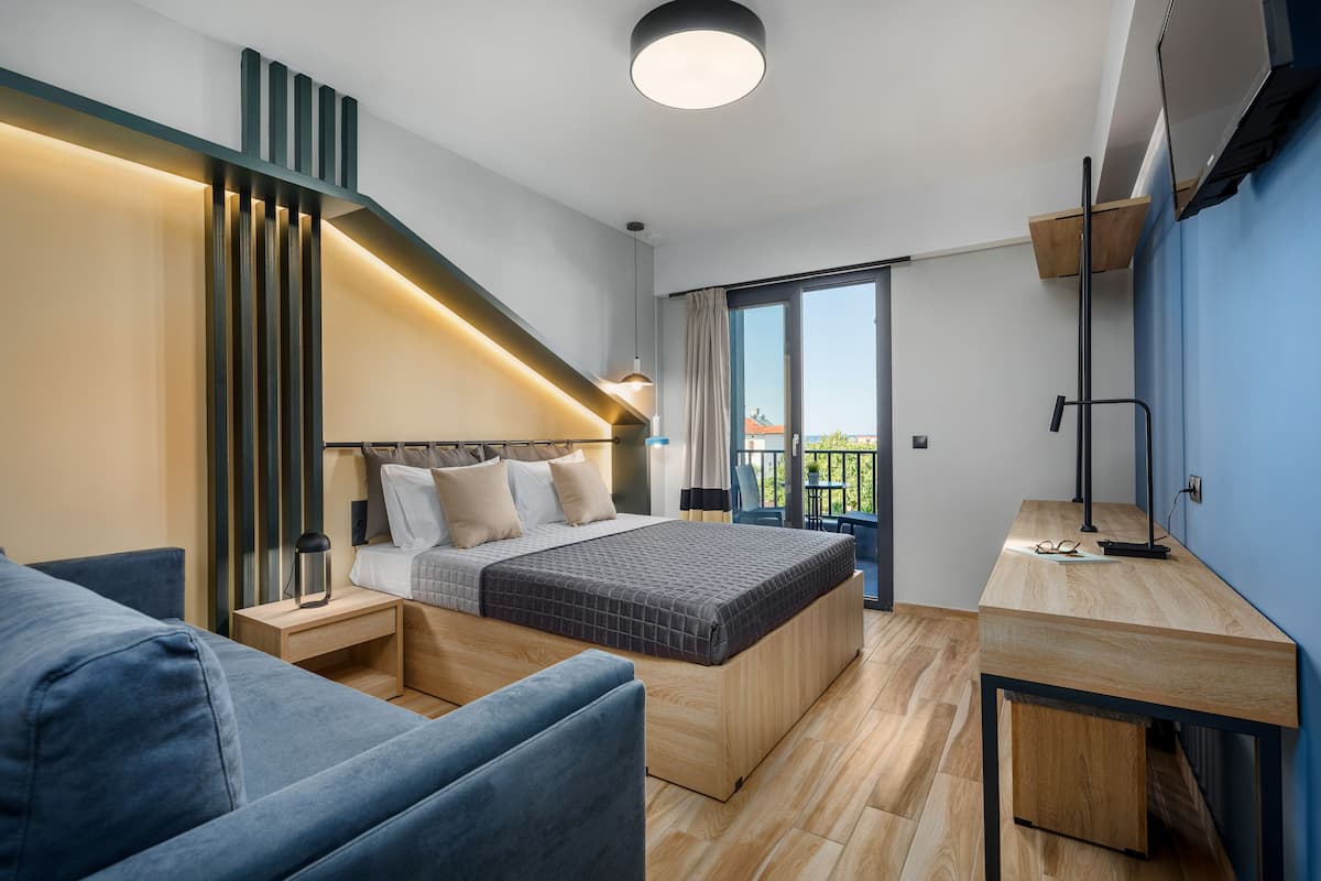 A modern bedroom with a bed, bedside tables, a desk, and a balcony.