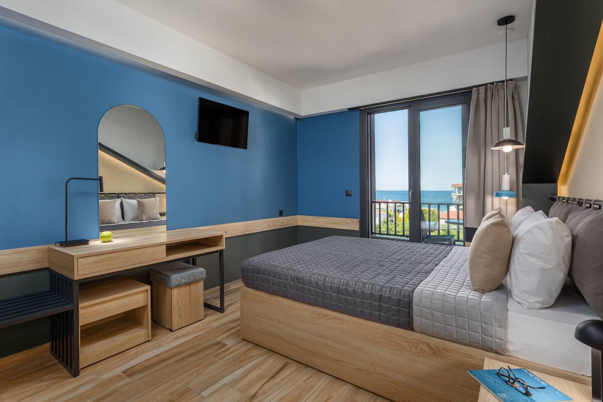 A modern bedroom with a large bed, a desk, and a TV.