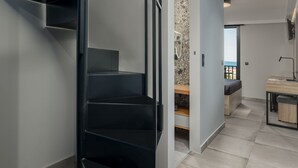 A modern interior with a spiral staircase, a stone wall, and a view through an open door. - Pidna (Dio-Olympos)