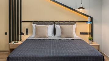 A modern bedroom with a large bed, a wooden headboard, a bedside table with a lamp, and a wall-mounted light fixture.