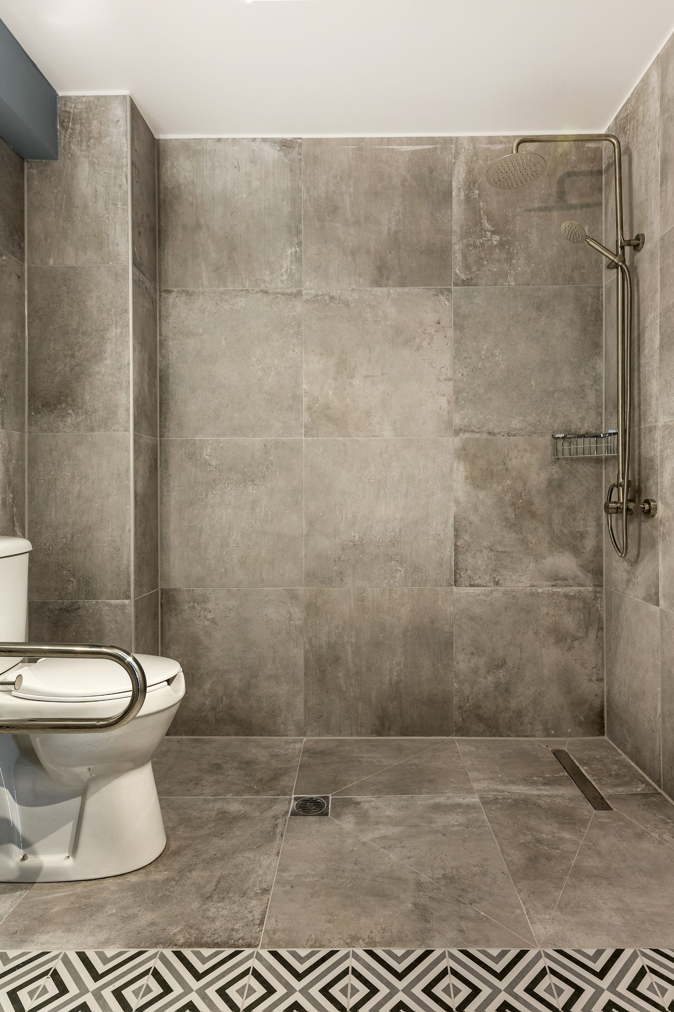 Une salle de bain avec des toilettes, une douche et un sol carrelé.