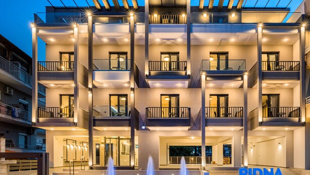 A multi-story hotel with balconies, a central courtyard with a fountain, and a sign reading "PIDNA". - Pidna (Dio-Olympos)