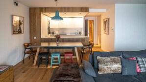 Un espace de vie moderne comprenant un coin cuisine, une table à manger et un canapé agrémenté de coussins.