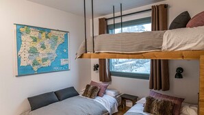 Une chambre avec des lits superposés, une carte accrochée au mur et une fenêtre avec des rideaux.