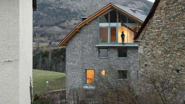 Un bâtiment en pierre avec un toit en bois et une grande fenêtre.