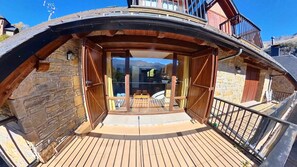 A wooden deck with a glass door leading to a room with a view of mountains.
