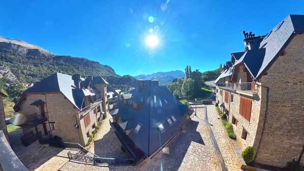 A town with stone buildings, a cobblestone street, and a mountain backdrop.