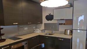Een moderne keuken met donkere kasten, granieten aanrecht, een roestvrijstalen oven, een spoelbak en een koelkast.