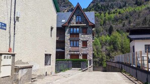 Un edificio de piedra con un balcón, rodeado por un paisaje montañoso.