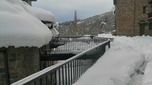 A snow-covered pathway leading to a stone building with a metal railing.