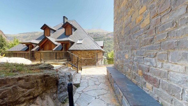 A stone building with a wooden staircase leading to a wooden deck.