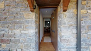 A stone-walled hallway leading to a room with a wooden floor and a visible 'B' sign.