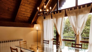 A dining area with a glass table, wooden chairs, a chandelier, and curtains. - Musales 24 - tucasaenlospirineos (Escarrilla)