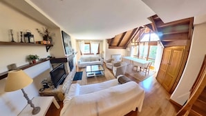 A cozy living room with a fireplace, a sofa, a dining table, and a TV. - Musales 24 - tucasaenlospirineos (Escarrilla)