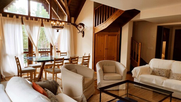 A cozy living room with a glass coffee table, two sofas, a dining table with chairs, and a staircase leading to an upper level. - Musales 24 - tucasaenlospirineos (Escarrilla)