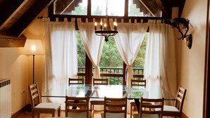 A dining area with a glass table and chairs, a chandelier, and a view of the outdoors through large windows. - Musales 24 - tucasaenlospirineos (Escarrilla)