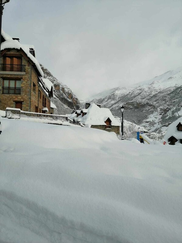 A snow-covered mountain village with stone buildings and a clear sky.