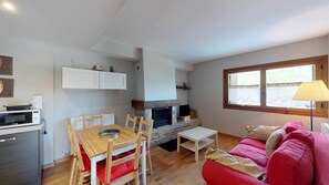 A compact living space with a dining area, a fireplace, a sofa, and a window with a view.