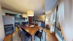 Una cocina moderna con armarios oscuros, una isla central y una zona de comedor con una mesa y sillas de madera.