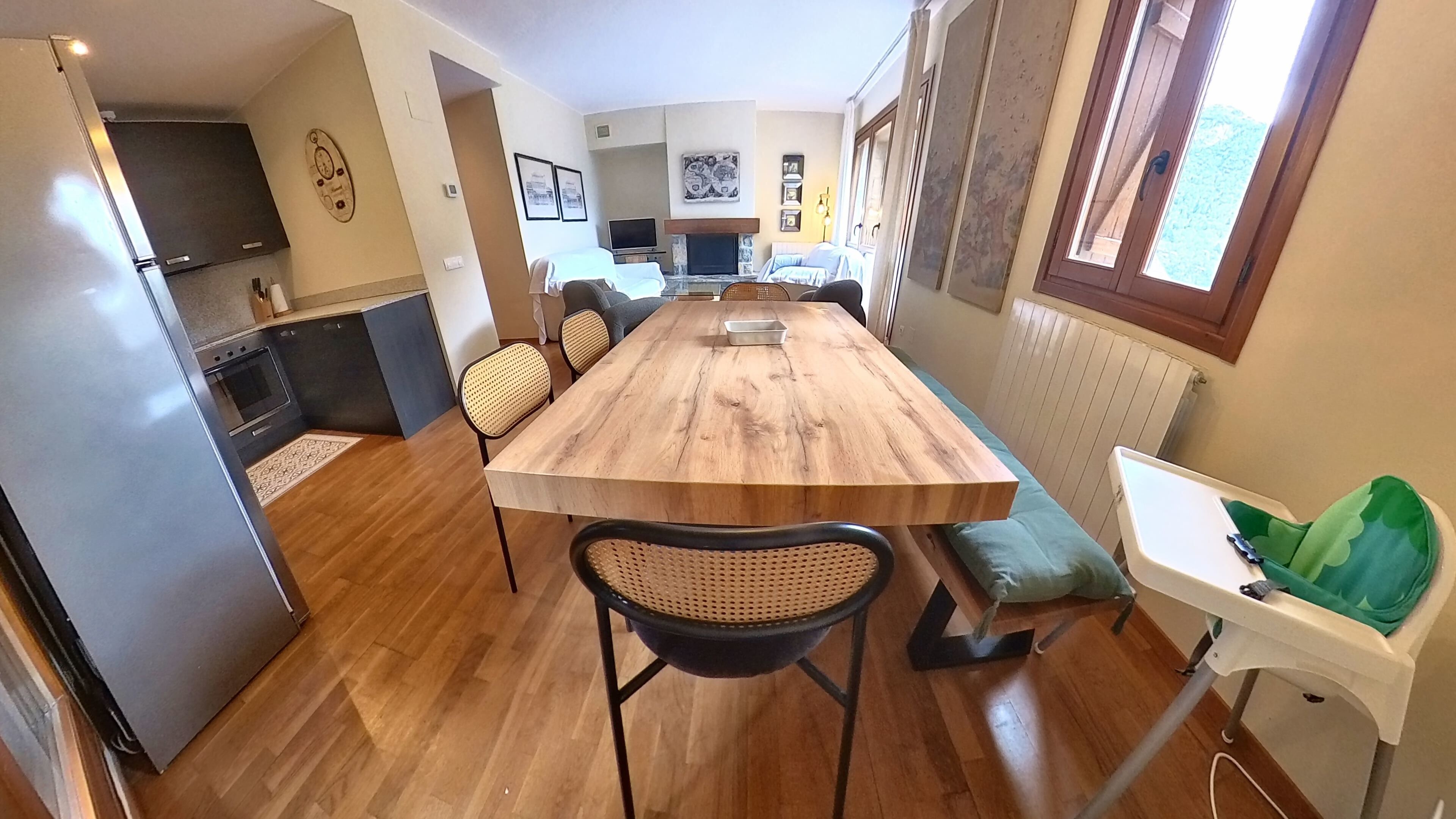 A modern kitchen with a wooden dining table, chairs, and a built-in oven.