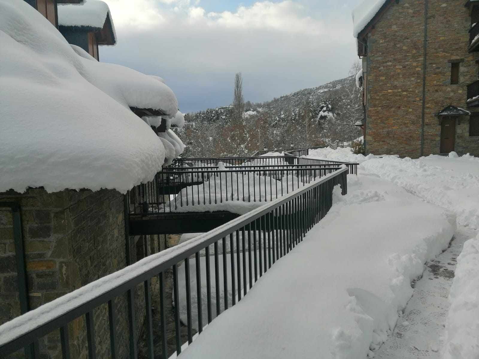 Een besneeuwde pad dat leidt naar een stenen gebouw met een metalen hekwerk.