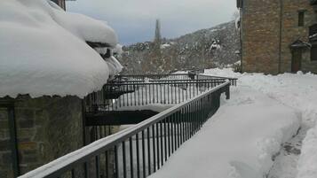 Een besneeuwde pad dat leidt naar een stenen gebouw met een metalen hekwerk.