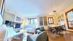 A living room with a fireplace, sofa, TV, and dining area with chairs and a table.