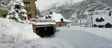 A snow-covered mountain village with stone buildings and a tunnel entrance.